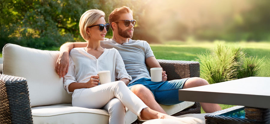 Couple relaxing on outdoor sofa in garden